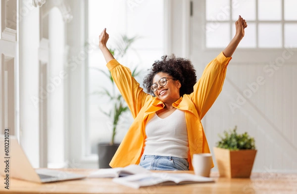 Fototapeta Joyful   business woman freelancer  entrepreneur smiling and rejoices in victory while sitting at desk   and working at laptop   after finishing project  in home office