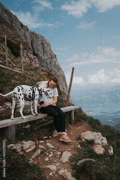 Fototapeta Wanderin mit Hund (Dalmatiner) auf Bank in den Bergen / Schweiz