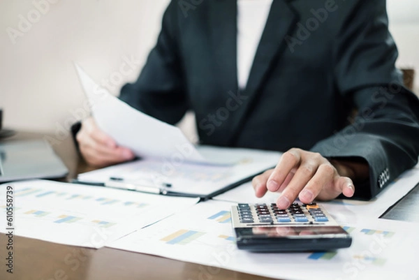 Fototapeta The businessman hand sits at their desks and calculates financial graphs showing the results of their investments planning the process of successful business growth