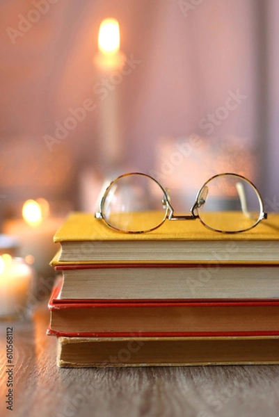 Fototapeta Cup of tea or coffee, plate of cookies, books, e-reader, pencil and lit candles on the table. Selective focus.