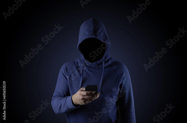 Fototapeta A hacker in a blue hood is holding a phone. Phone fraudster.