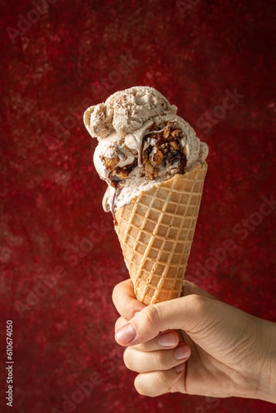 Fototapeta mano de una mujer soteniendo un cono de helado sobre un fondo rojo con textura