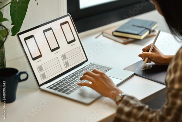 Fototapeta Side view of female website developer planning application development for web mobile phone at workplace