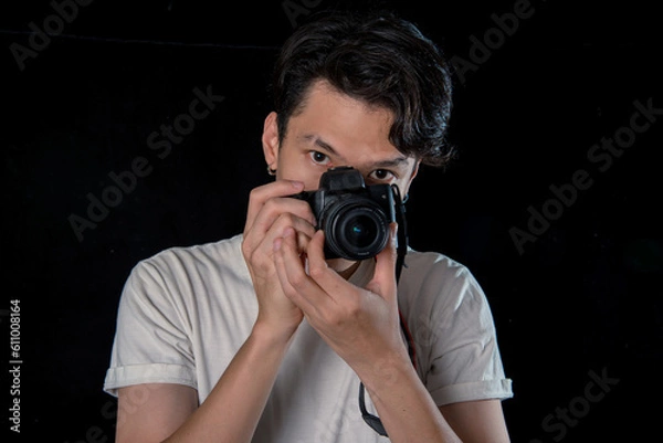 Obraz Portrait of men  holding a DSLR  looking camera  on dark studio background , asian