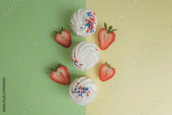 Fototapeta Cupcakes with strawberrie stand on a colored background. Next to the American flag