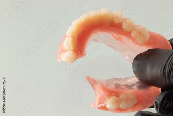 Obraz Woman holding a broken lower complete denture. Selective focus.