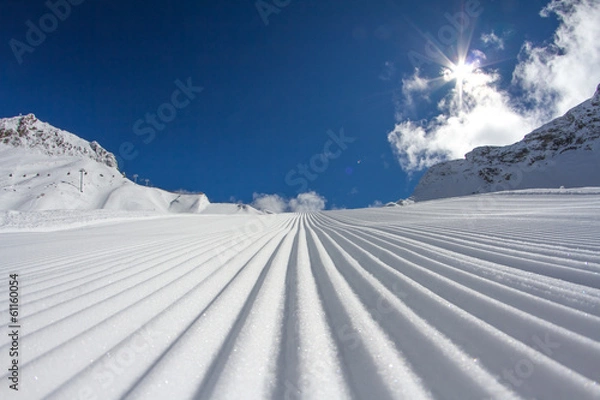 Fototapeta Fresh snow groomer tracks on a ski piste
