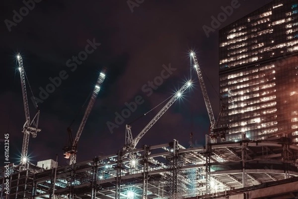 Obraz Moscow, Russia - 8 June 2023: Night photo of a skyscraper under construction in the center of Moscow, on the roof of which there are large cranes, Moscow City.