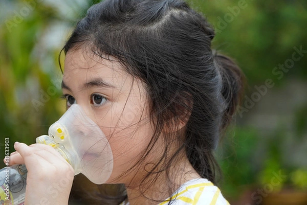 Fototapeta Cute asian girl with asthma using inhaler and spacer,Respiratory system and allergies