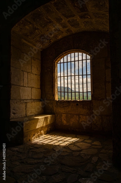 Fototapeta A dark prison room with bars preventing escape. Cold tower in castle in Spain. Cold stone walls.