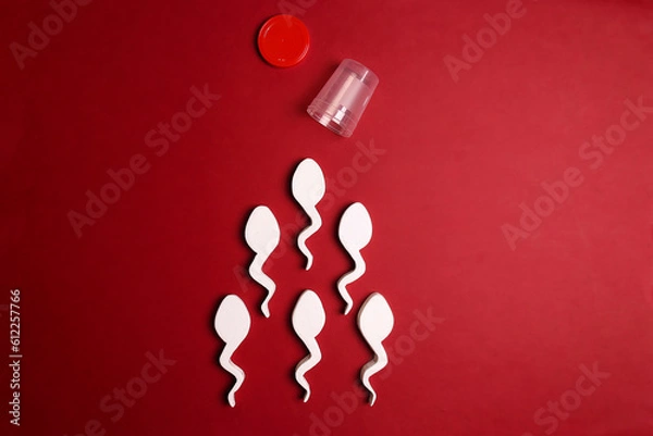 Obraz Spermatozoa and sperm sample plastic container on red background.