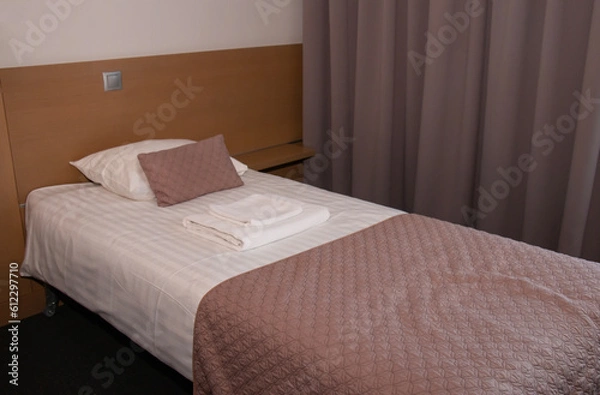 Fototapeta single bed for one person, covered with a bedspread and two towels