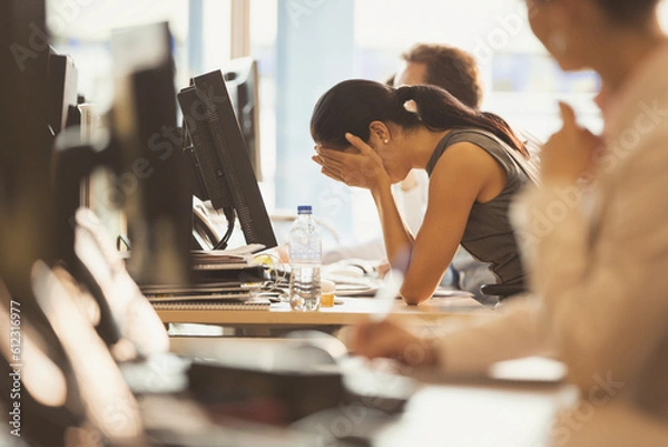 Obraz Stressed businesswoman with head in hands at office desk