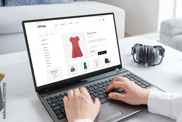 Fototapeta Woman purchasing a stunning red dress online with laptop computer. Modern ecommerce web page interface