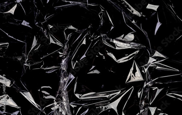 Fototapeta Wrinkled plastic wrap texture on a black background. Transparent cellophane package wallpaper

