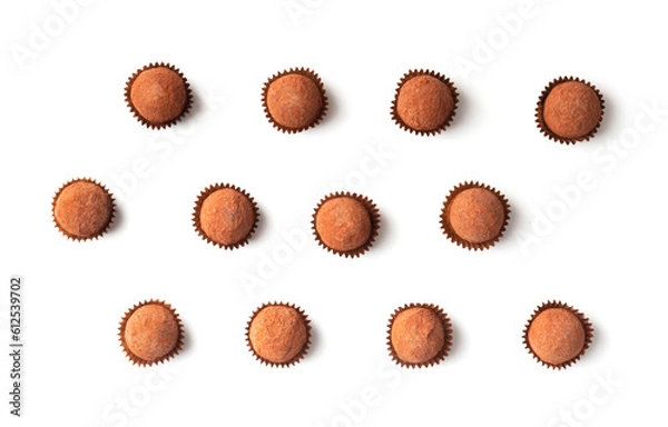 Fototapeta Chocolate truffles in individual paper baskets on a white background, top view.