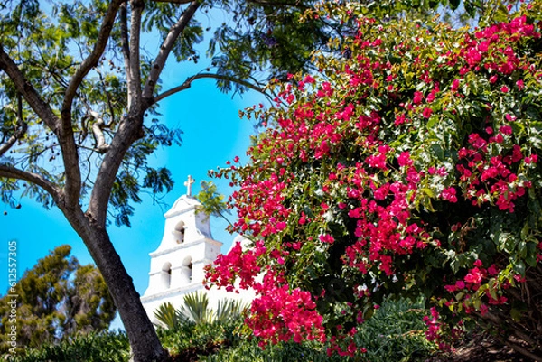 Obraz Bright Pink Bougainvillea Flowers Bloom and Contrast against a Bright Blue Sky at the White Façade of the Mission Basilica San Diego de Alcala in San Diego, California, USA