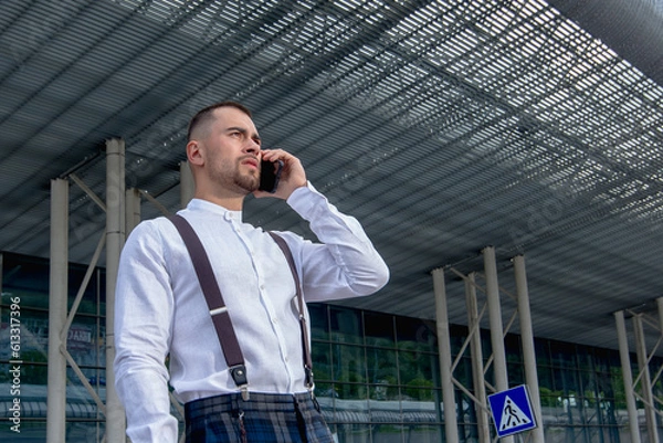 Fototapeta a handsome man nicely and stylishly dressed in pink glasses stands at a bus stop