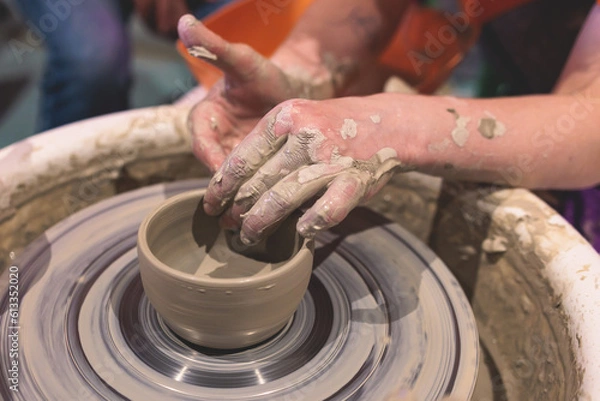 Fototapeta Pottery lesson master class for kids children, process of making clay pot on pottery wheel, potter wet hands creating ceramic crockery handcrafts, ceramist molding jar or vase