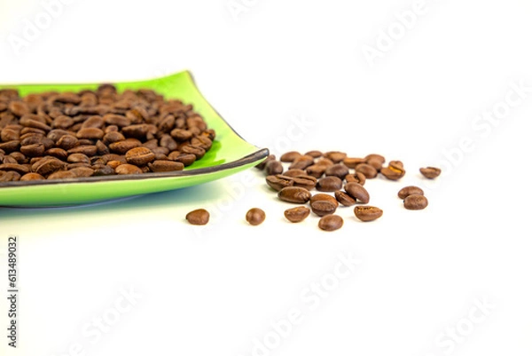 Fototapeta Coffee beans on a green square saucer, white background