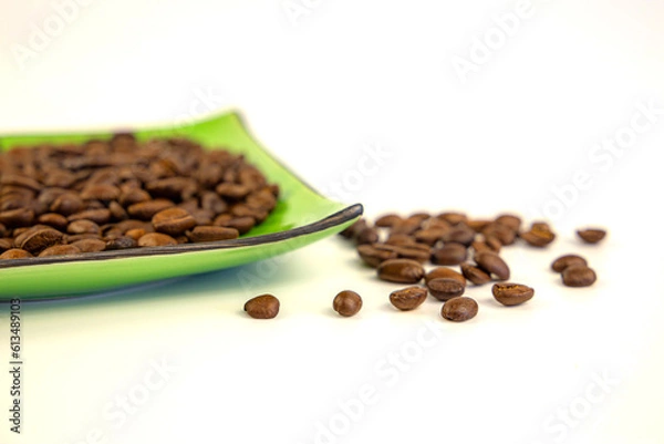 Fototapeta Coffee beans on a green square saucer, white background