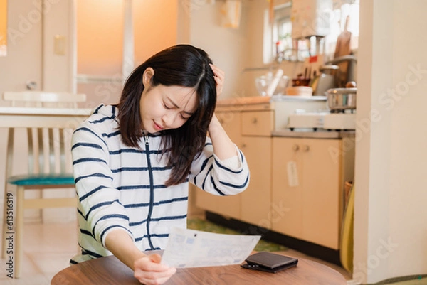 Fototapeta 電気料金の高騰で頭を抱える若い女性