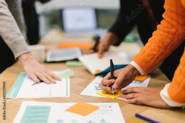 Fototapeta hands of colleagues working on projects using paper data and writing notes