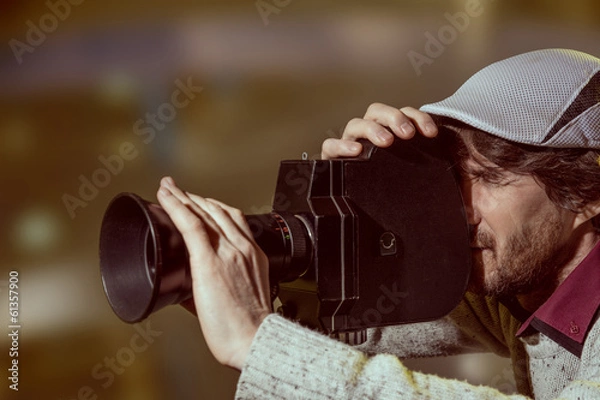Fototapeta A man wearing a cap with an old movie camera