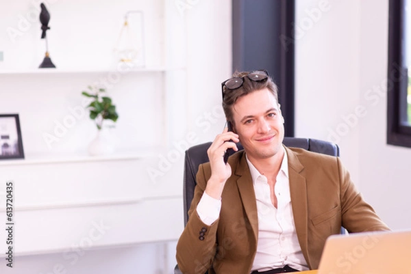 Obraz Businessman in brown suit color using mobile phone in modern office