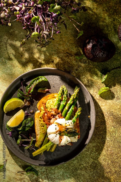 Fototapeta Grilled Toast witch Asparagus, avocado, Poached egg, greens, bacon on green textured background. banner, menu recipe place for text, top view. Traditional breakfast.