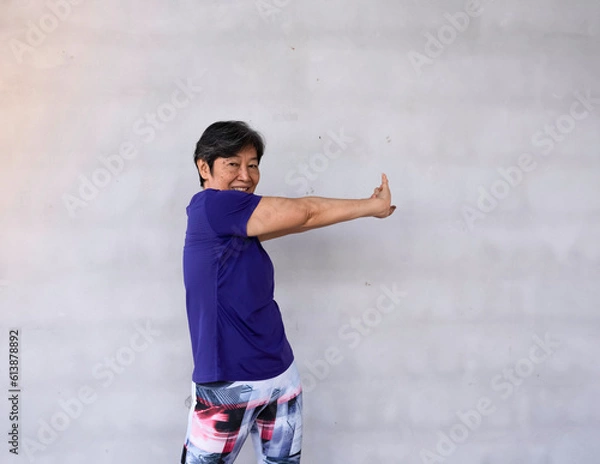 Fototapeta Old lady clasp hands and twist body to the right side,for stretching body before exercise