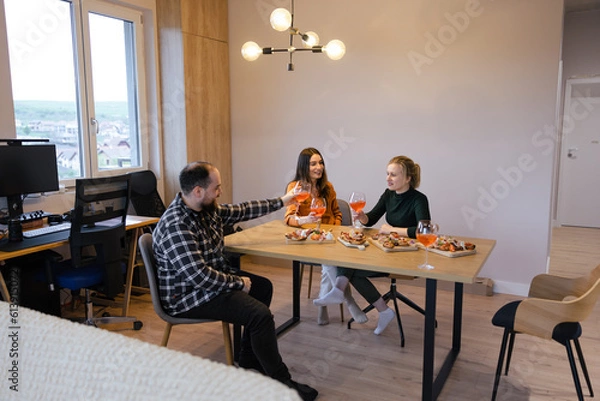 Obraz Friends Delighting in Good Food and Company. Group of three friends enjoying time together at the table