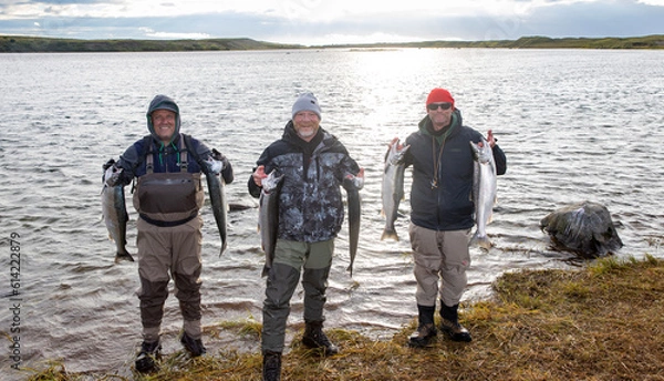 Obraz Three brothers holding their fresh catch of coho salmon on the shore of the Egegik river in Alaska