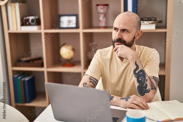 Fototapeta Young bald man using laptop sitting on table at home