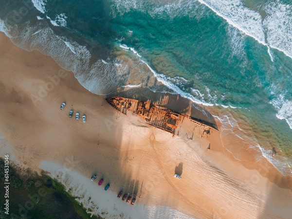 Fototapeta High angle aerial bird's eye drone view of the Maheno shipwreck on Seventy-Five Mile Beach on Fraser Island, Queensland, Australia. Beautiful sunset light with waves.
