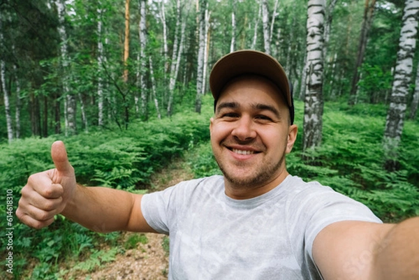 Fototapeta Man smiling and taking a selfie in the forest