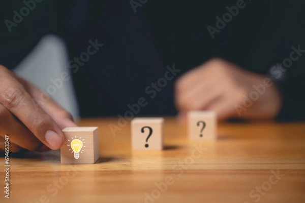 Fototapeta Creative consulting and innovative solutions. Hand holding wooden block with glowing light bulb icon. Business strategy suggestion for new initiative. Success through imagination and expertise.