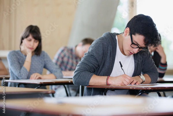Obraz Focused male college student taking test at desk in classroom