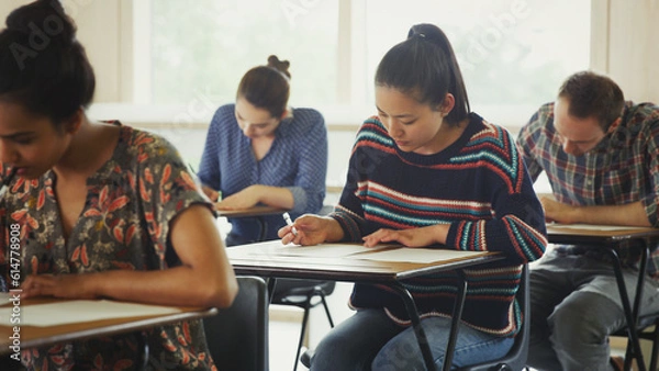 Obraz College students taking test at desk in classroom
