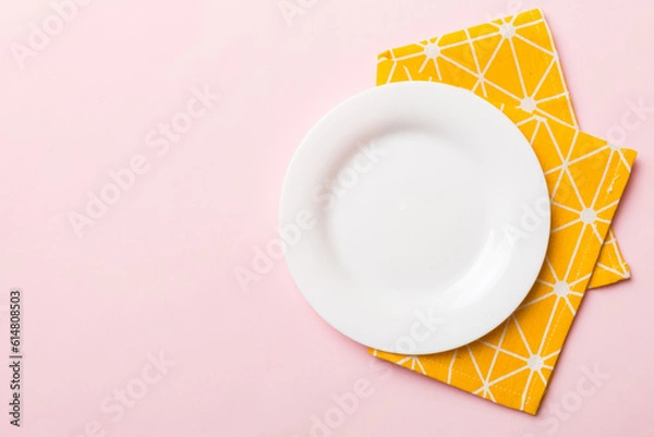 Obraz Top view on colored background empty round white plate on tablecloth for food. Empty dish on napkin with space for your design