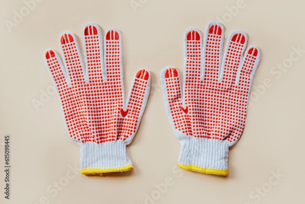 Fototapeta Red gardening gloves on a beige background. Top view, close-up.