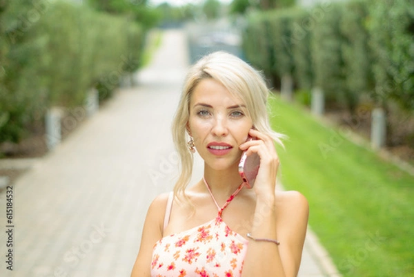 Fototapeta PRETTY GIRL SMILING WHILE IS TAKING A SELFIE AND CALLING BY PHONE IN THE STREET