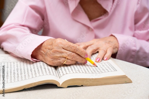 Fototapeta Hands of senior people solving together a word search quiz at nursing home. High quality photo