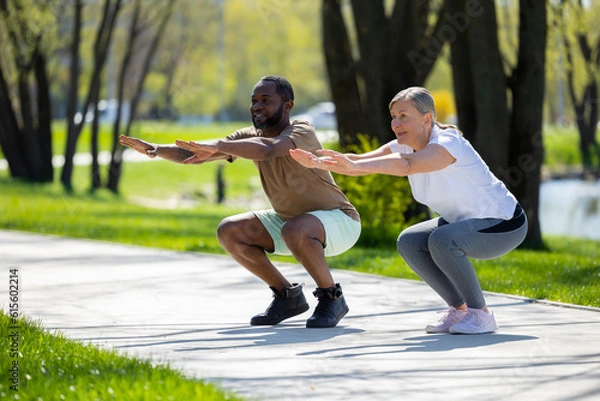 Fototapeta Couple exercising in the park and doing squats