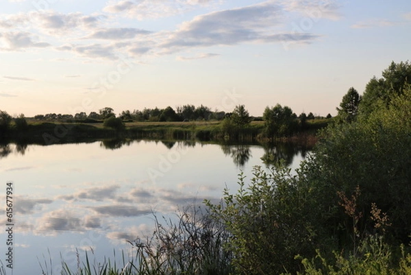 Obraz Reflections of clouds and trees in the mirror of the water of the lake