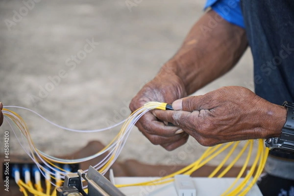 Fototapeta Technician is using duct tape. with fiber optic cable before installing into the FTTH terminal box.
