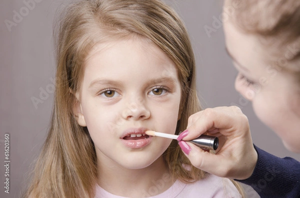 Obraz Визажист наносит блеск на губы девочки