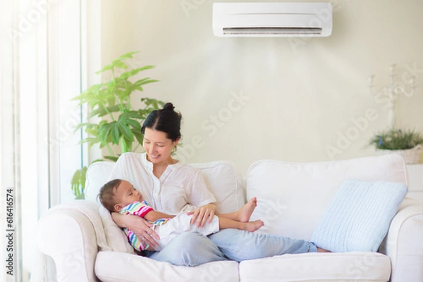 Fototapeta Mother and child with air conditioner remote