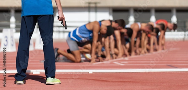 Fototapeta Athletes ready to start in blocks, starter with gun, official prepares to start a race