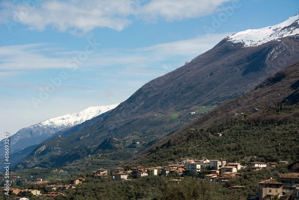 Fototapeta Picturesque Italian foothills with hotels and private houses located under the mountain against the background of the blue sky